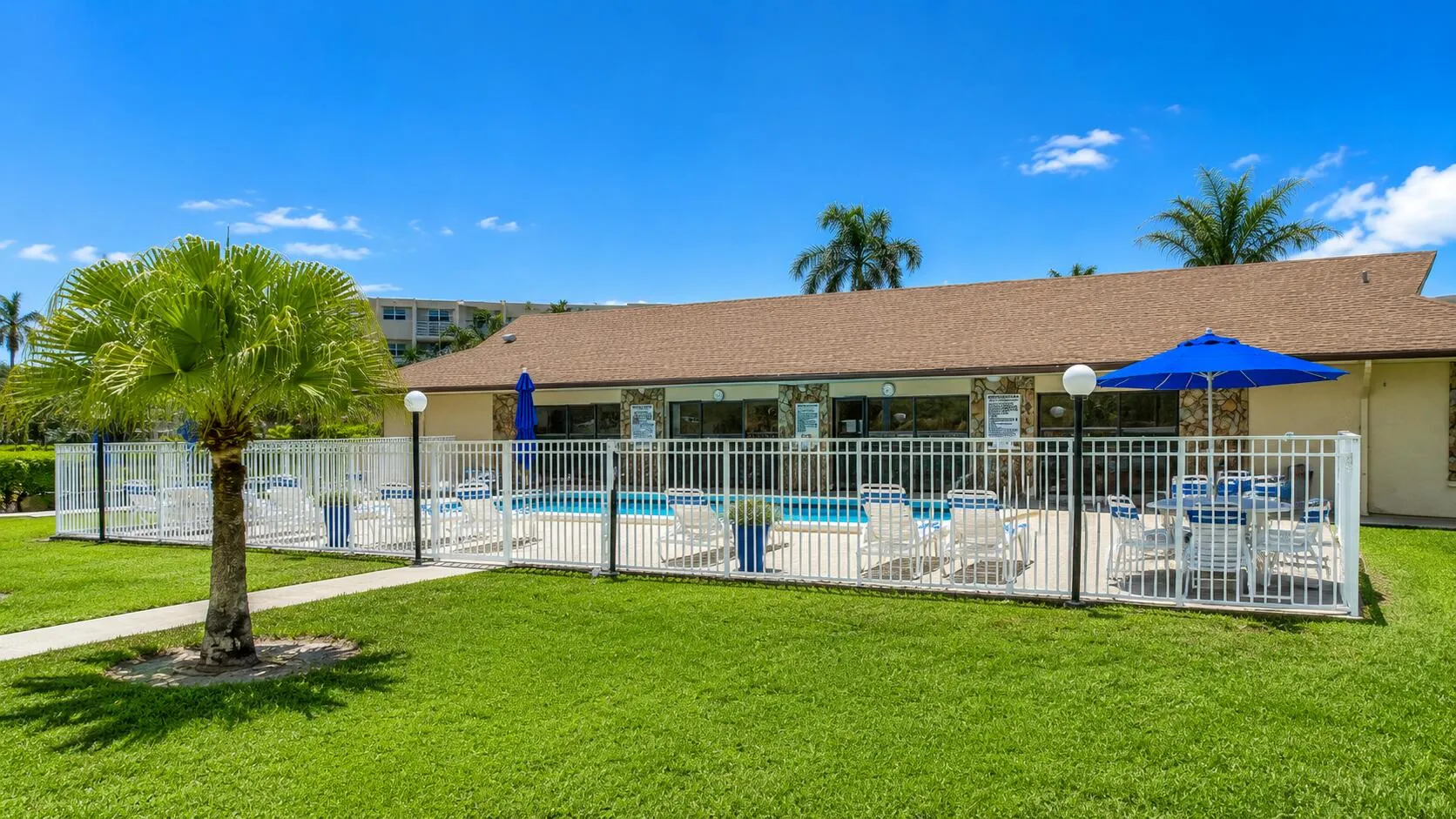 Community pool featuring a white perimeter fence and manicured landscaping