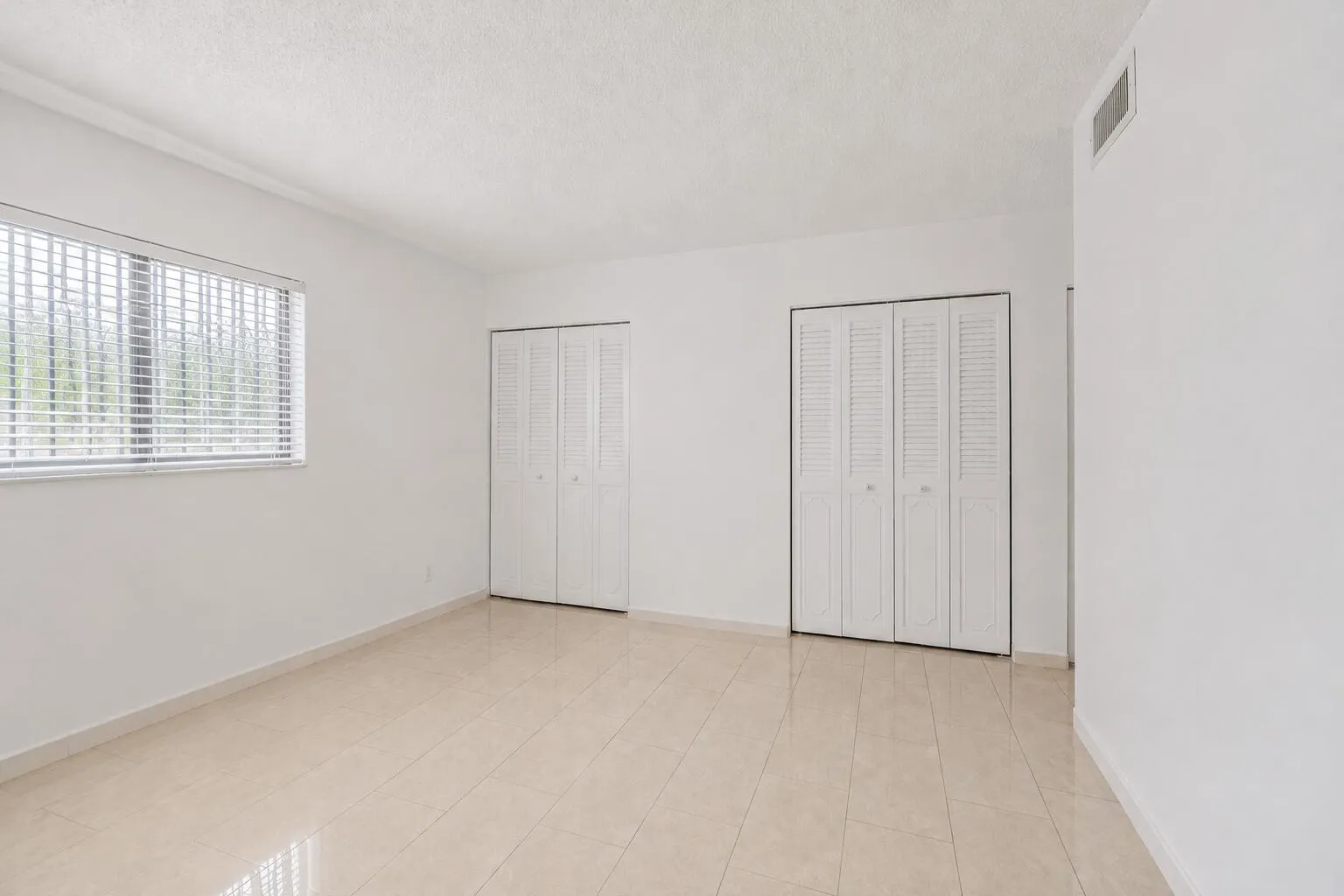 Bright, light-filled room featuring ceramic tile flooring, and clean white walls