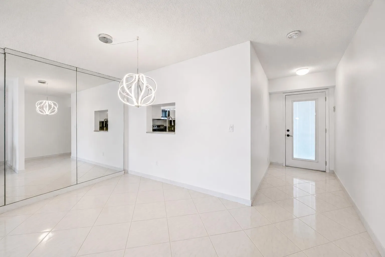 Bright, open entryway showcasing polished tile flooring, recessed ceiling lighting, and clean white walls