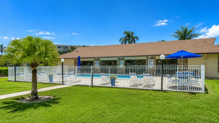 Community pool featuring a white perimeter fence and manicured landscaping