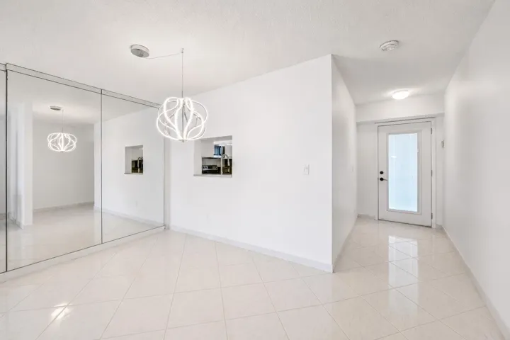Bright, open entryway showcasing polished tile flooring, recessed ceiling lighting, and clean white walls