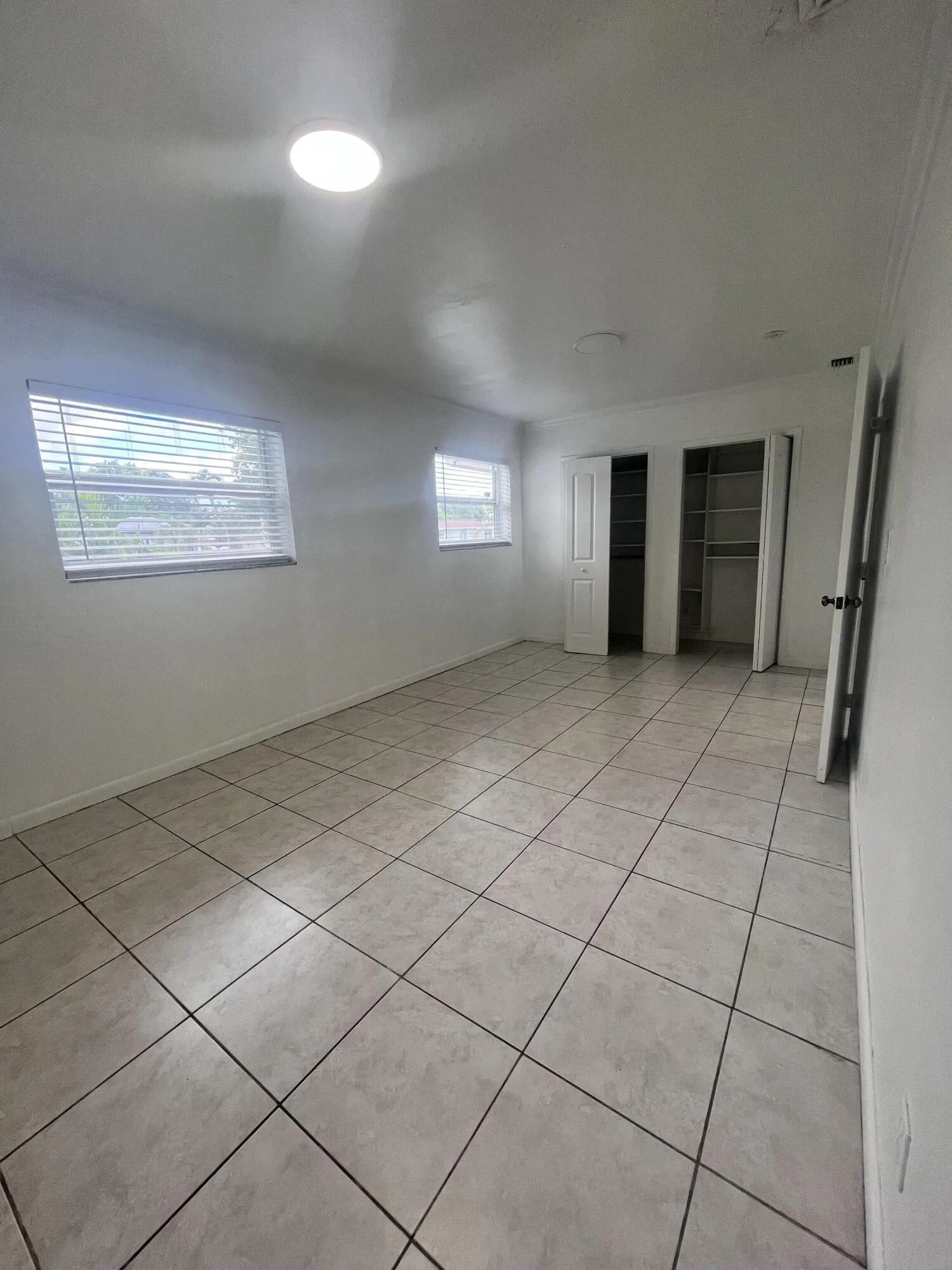 Recessed ceiling lighting, tiled flooring, multiple windows, and two built-in closets