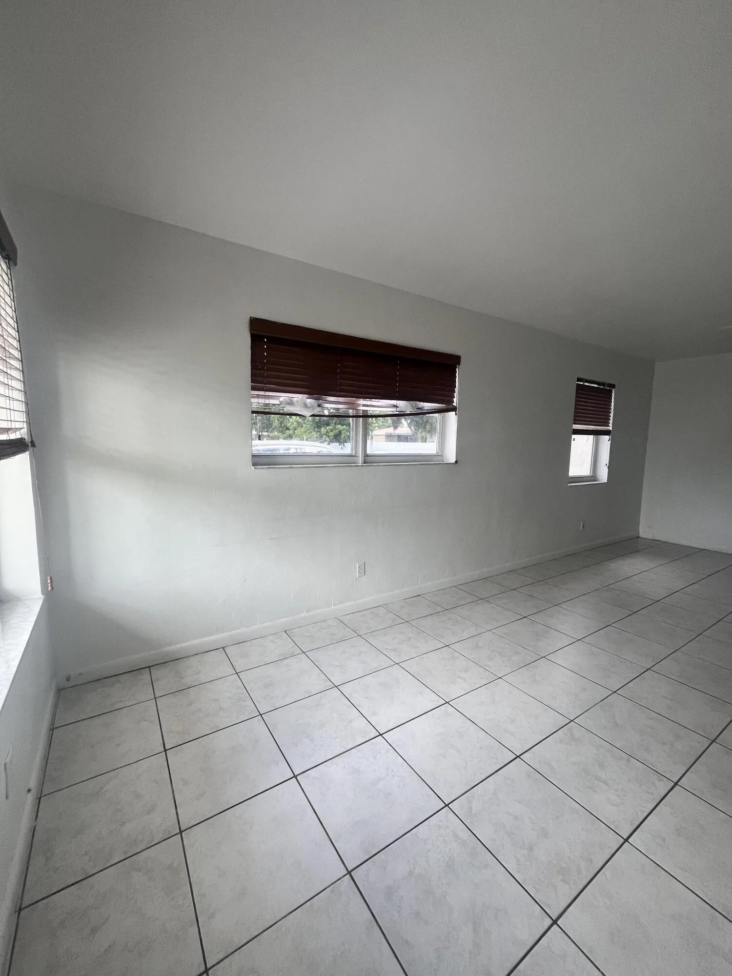 White wall finishes, multiple windows, and light-toned tile flooring