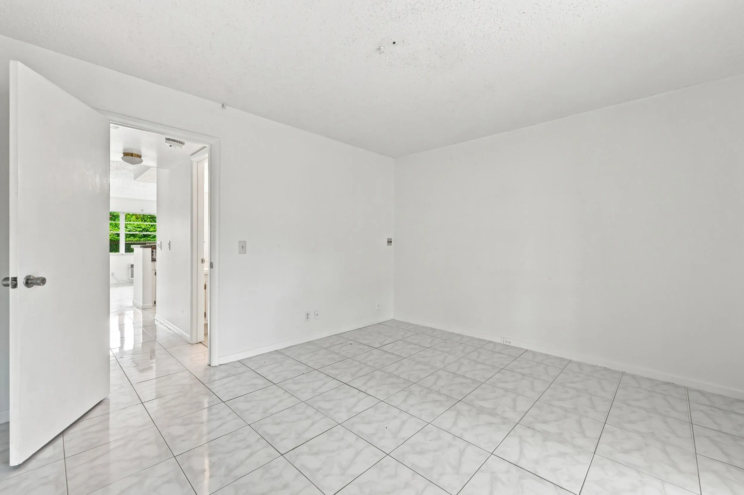 Spacious bedroom featuring tile flooring, an expansive mirrored closet for generous storage, and sliding glass doors opening directly to the enclosed patio. Abundant natural light and lush tropical views create a bright, inviting retreat.