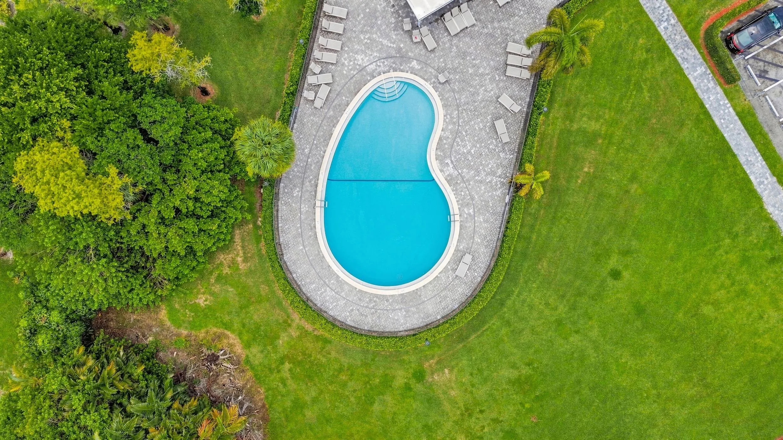 Aerial views showcase the expansive community pool and spacious surrounding sundeck, complete with abundant lounge areas, a covered seating pavilion, tropical landscaping, and plenty of space to relax and enjoy the South Florida sunshine.