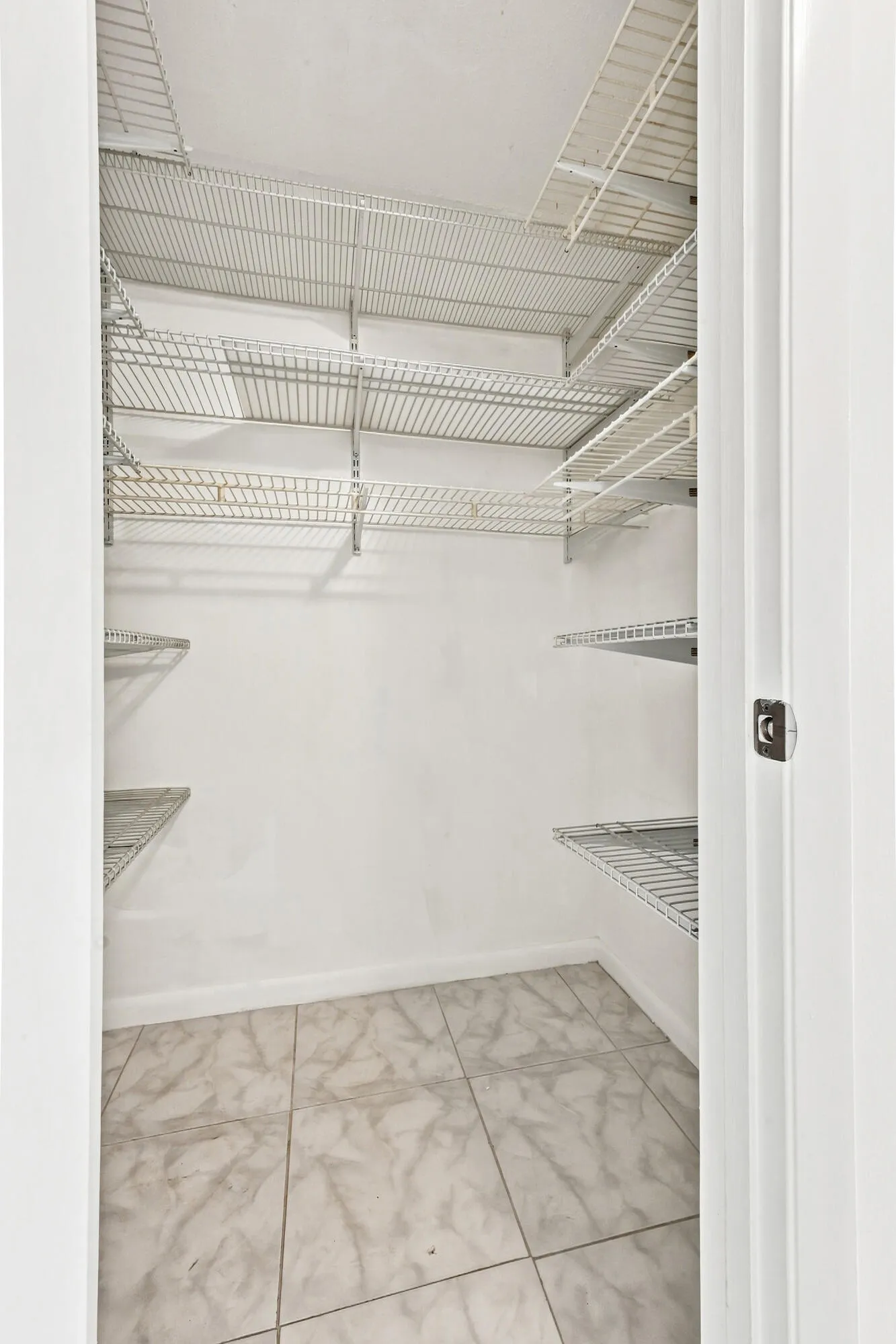 Generously sized walk-in closet featuring extensive built-in shelving, providing excellent storage and organization space.