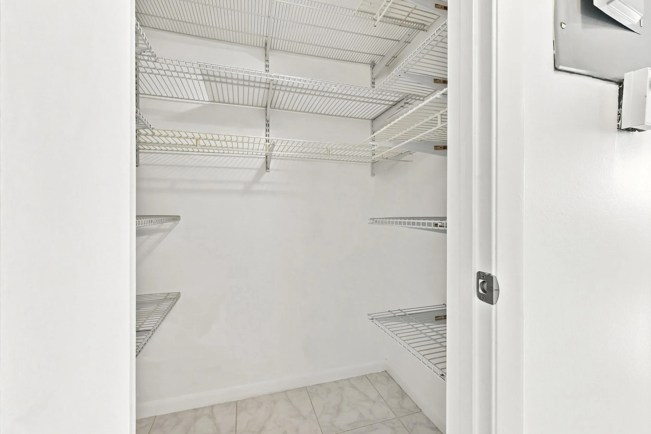 Generously sized walk-in closet featuring extensive built-in shelving, providing excellent storage and organization space.