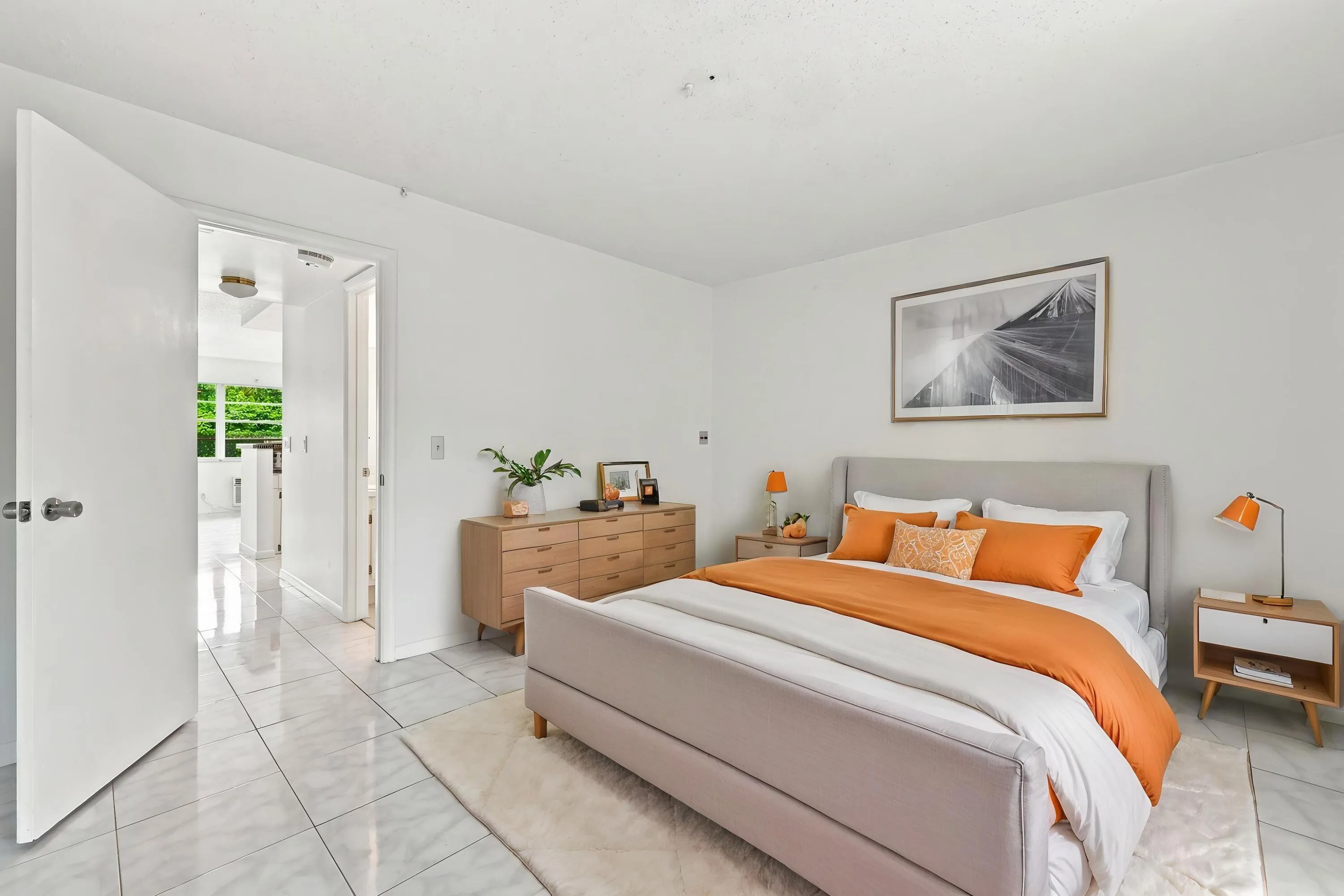 Spacious bedroom featuring tile flooring, an expansive mirrored closet for generous storage, and sliding glass doors opening directly to the enclosed patio. Abundant natural light and lush tropical views create a bright, inviting retreat.