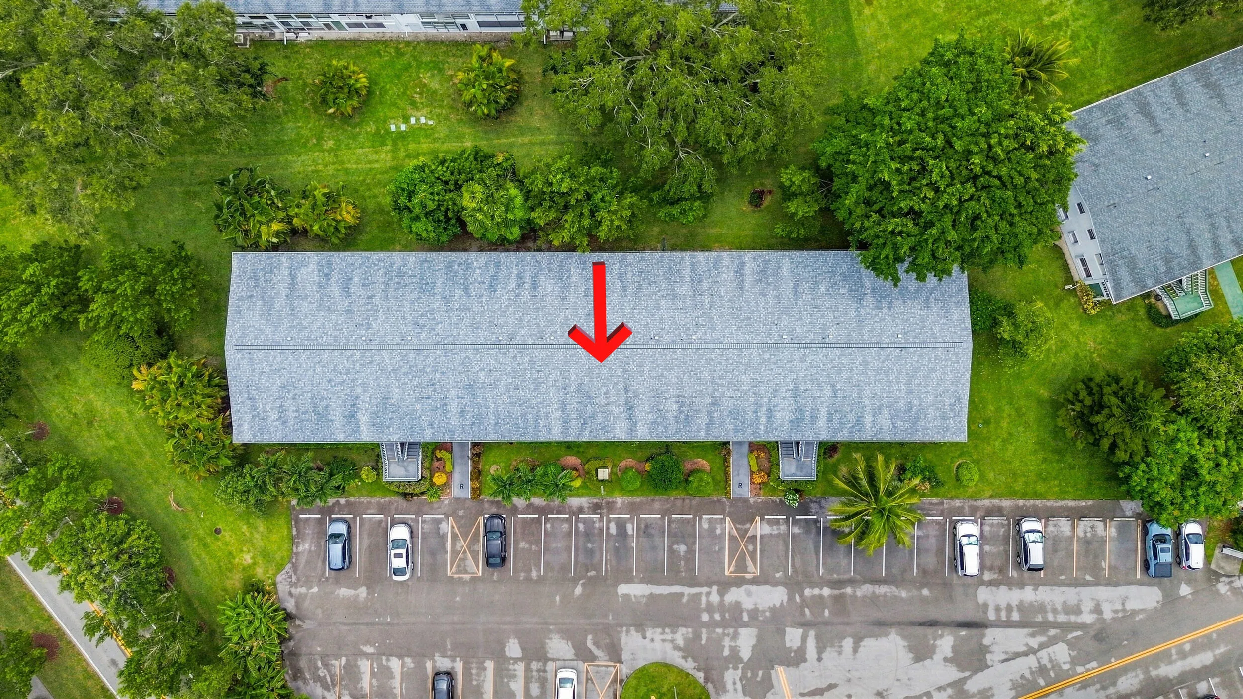 Expansive aerial views showcase the residence within a beautifully maintained community surrounded by mature trees, tropical landscaping, open green space, and convenient resident parking. The highlighted building offers a peaceful setting within the community while remaining easily accessible to the surrounding area.