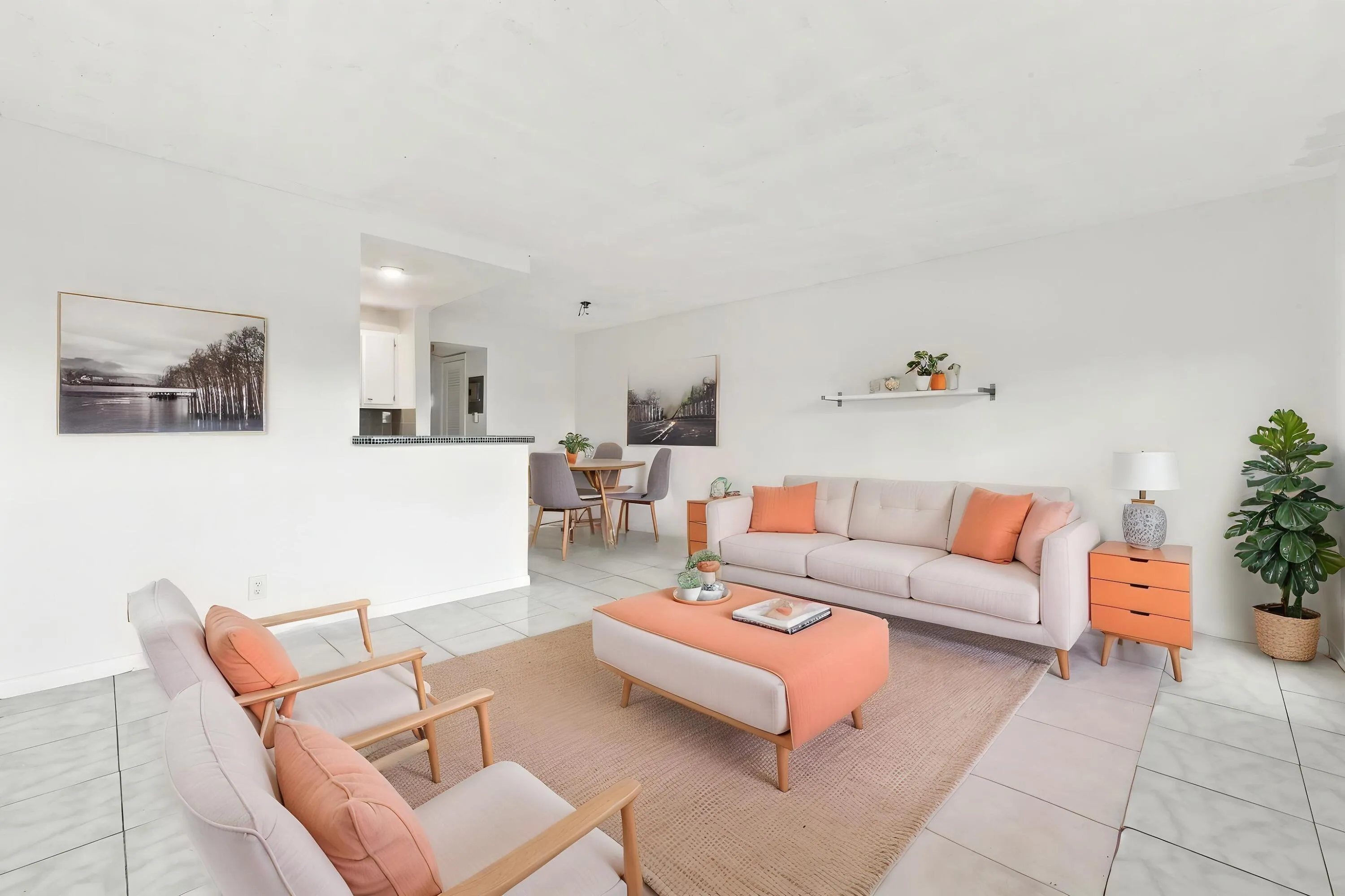 Spacious and bright living area featuring tile flooring throughout, abundant natural light, and a large wall of windows overlooking lush tropical greenery. The open layout flows seamlessly into the kitchen and offers plenty of flexibility for comfortable everyday living and entertaining.