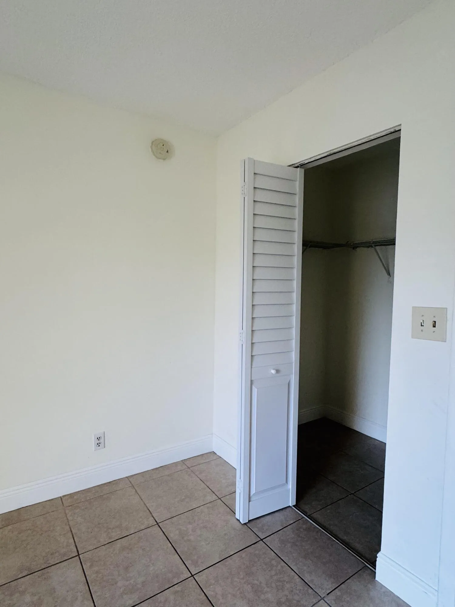 Tile flooring, closet with bi-fold louvered doors, built-in shelving, and light-toned wall paint