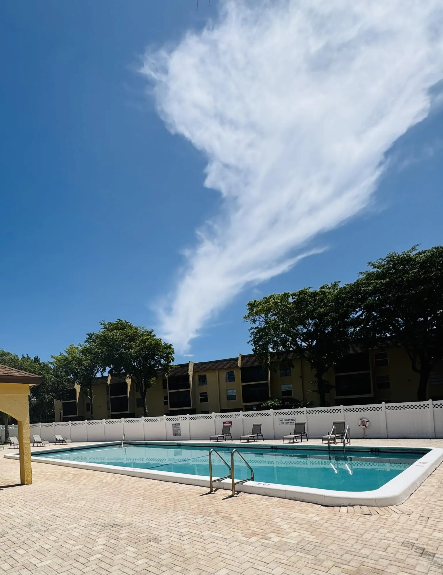 Resort-style swimming pool featuring crystal-clear water, brick paver decking, and integrated ladder entry, picnic & grill area to the left.
