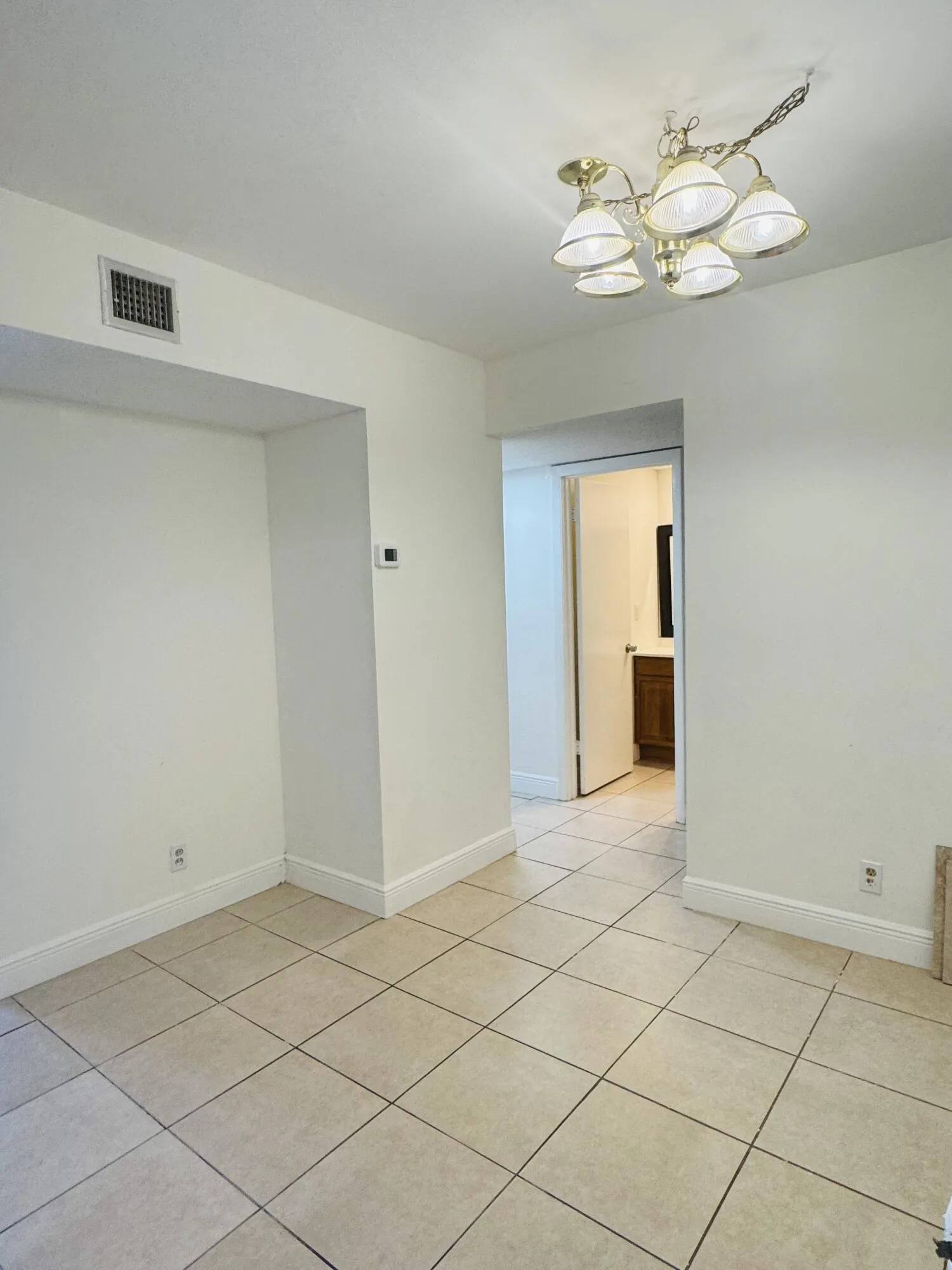 Neutral tone wall finishes, tiled flooring, and a five-light ceiling fixture