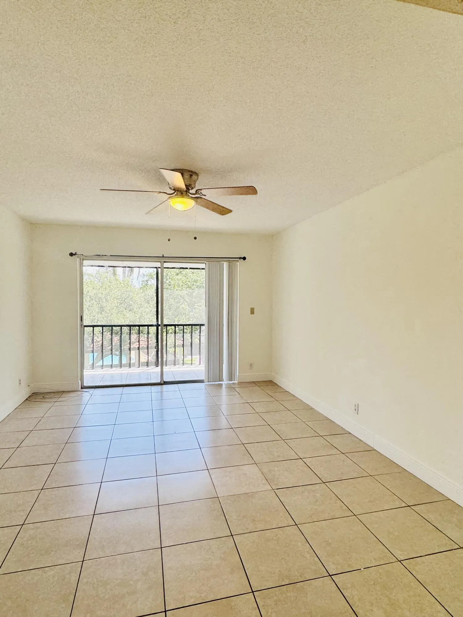 Tile flooring, sliding glass door, overhead lighting, ceiling fan, balcony with iron railing