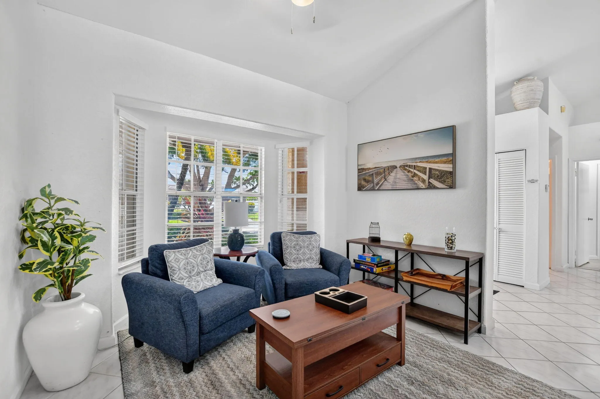 Bay windows with blinds, vaulted ceiling, tile flooring, and a ceiling fan