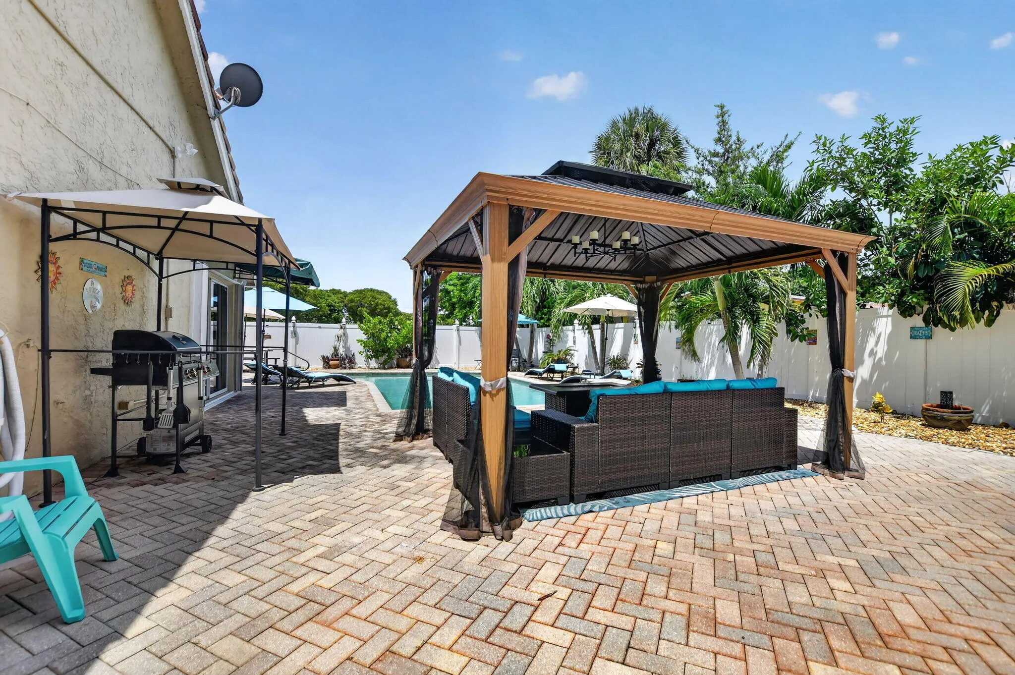 Brick paver patio featuring a covered gazebo with integrated lighting, a swimming pool, and a privacy fence