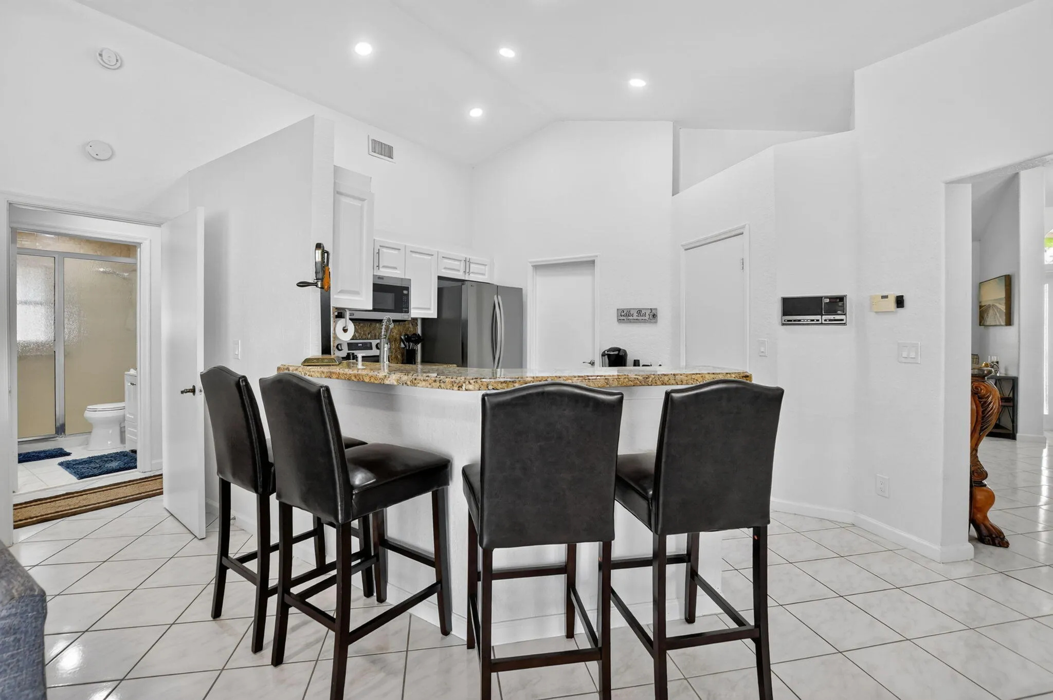 Kitchen with white cabinetry, stainless steel appliances, and a breakfast bar featuring a speckled countertop