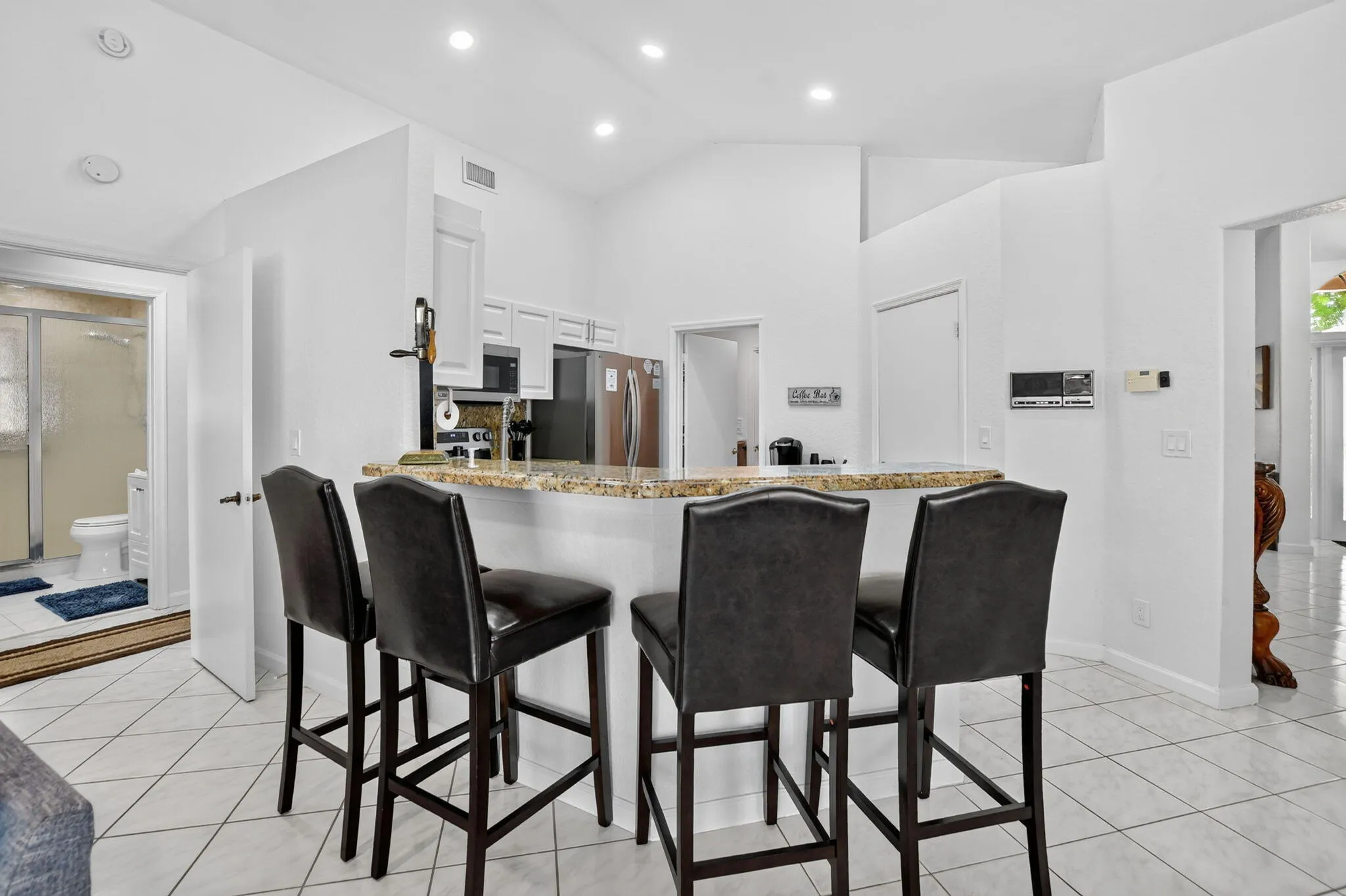 Kitchen featuring a breakfast bar with stone countertop, white cabinetry, stainless steel appliances, and recessed lighting