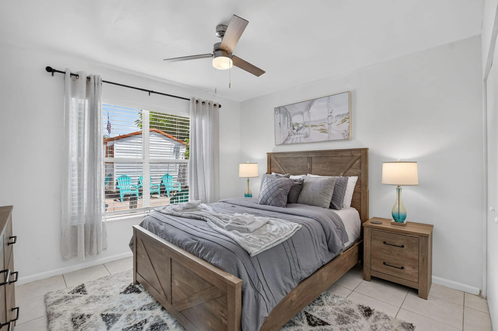 Neutral-toned walls, wood-finish ceiling fan, window with blinds, and light-colored tile flooring