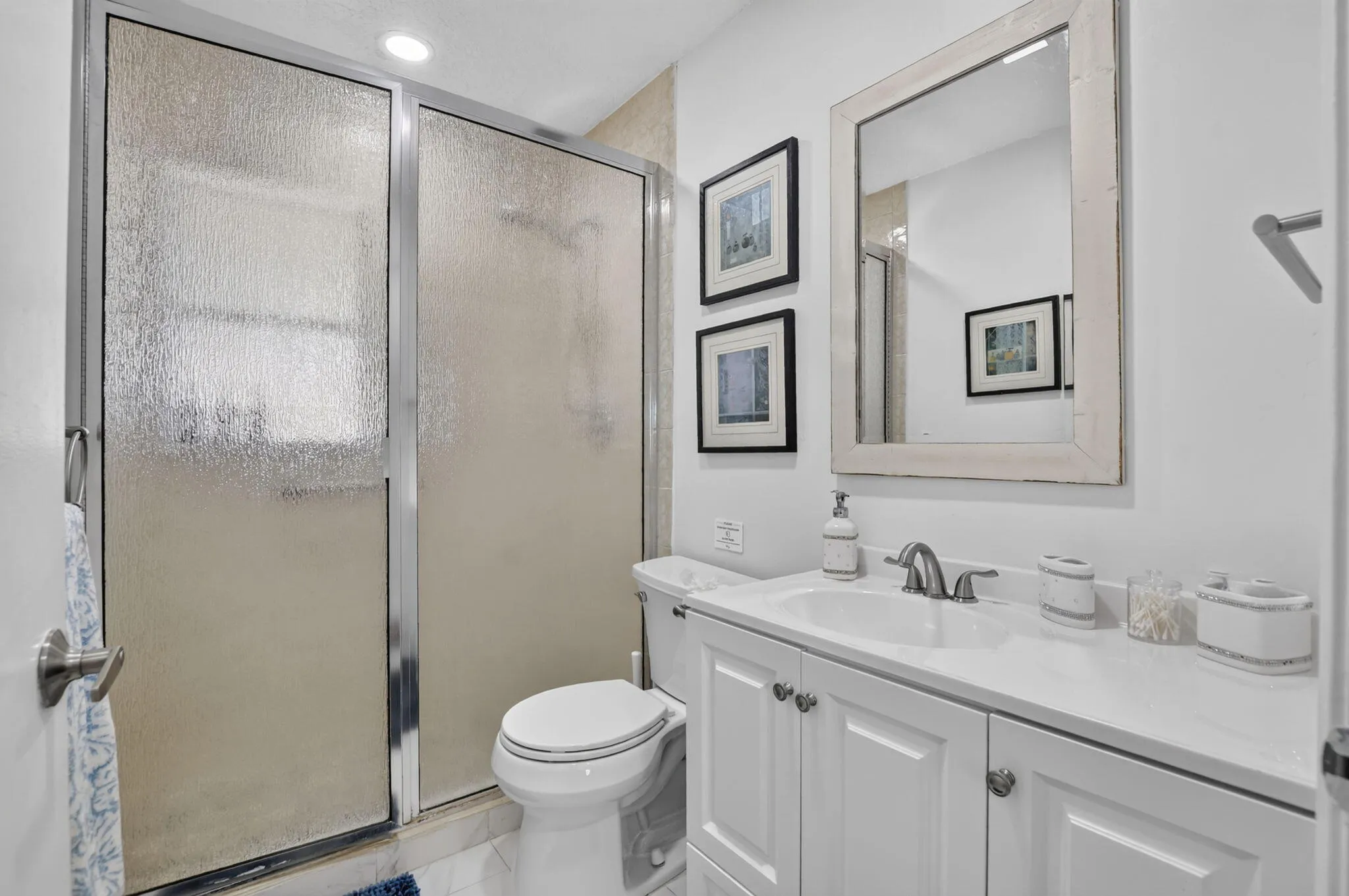 White vanity with panel cabinetry and a light-toned countertop