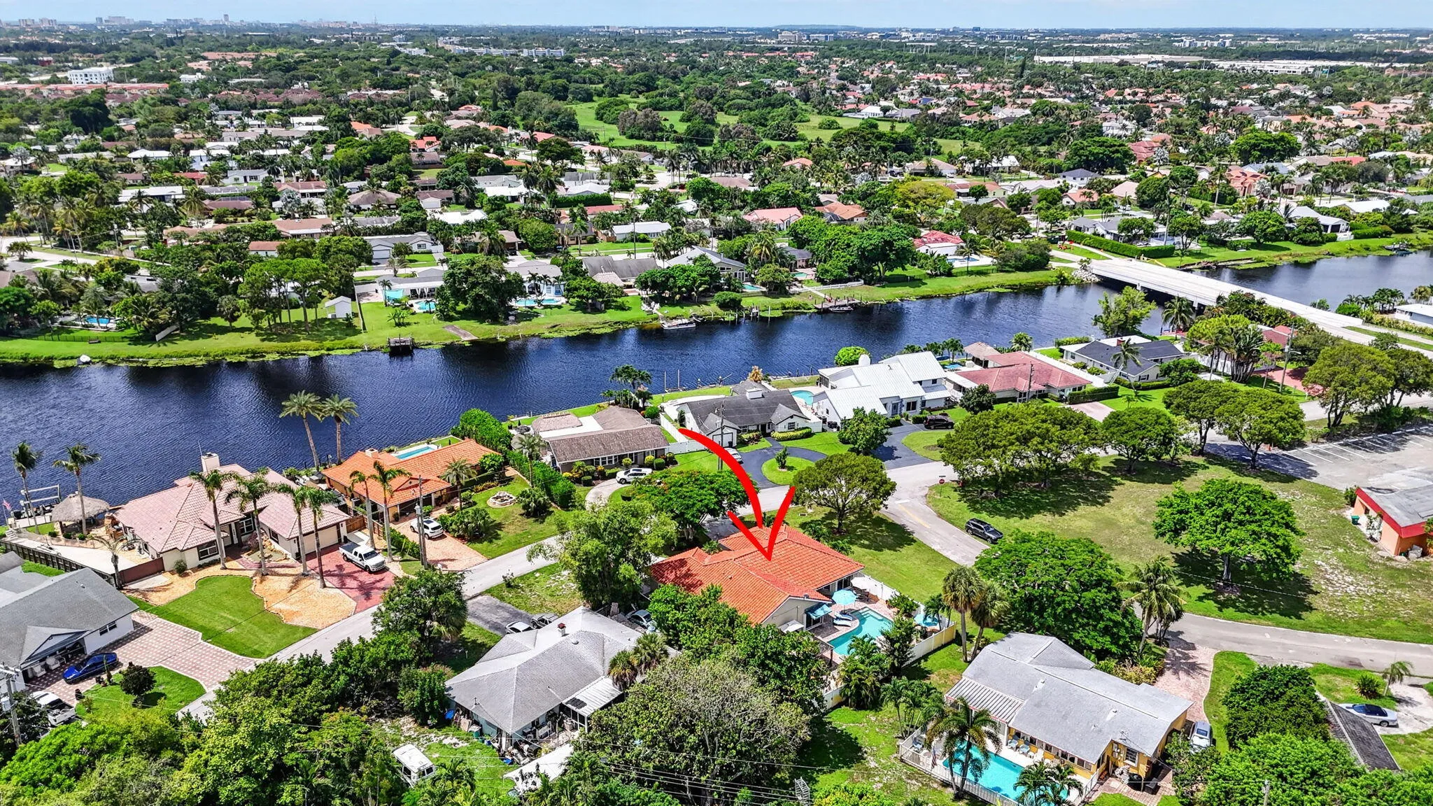 Aerial perspective showcasing the property with a private pool, surrounded by lush landscaping and a developed residential area