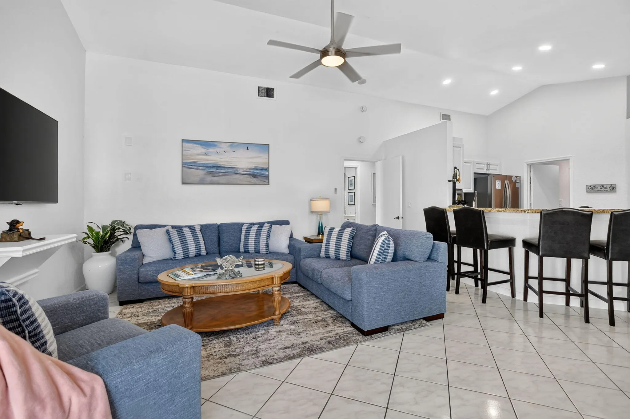 Vaulted ceilings, contemporary ceiling fan, recessed lighting, tile flooring, and a kitchen island with bar seating