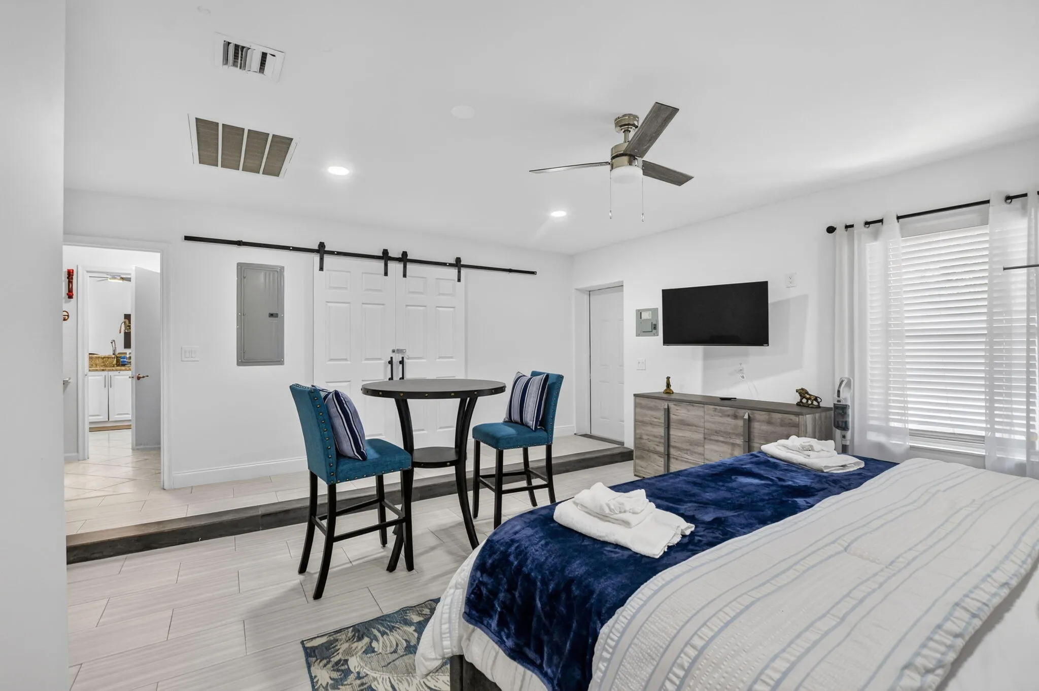 White walls with recessed lighting, tile flooring, barn door entry, ceiling fan, and a built-in media console