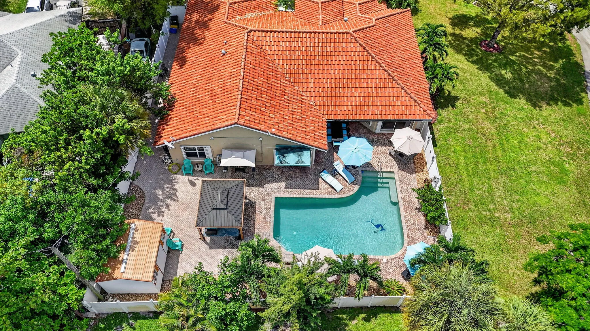 Terracotta tile roof, freeform swimming pool, spacious paver patio, lush landscaping, and a detached gazebo
