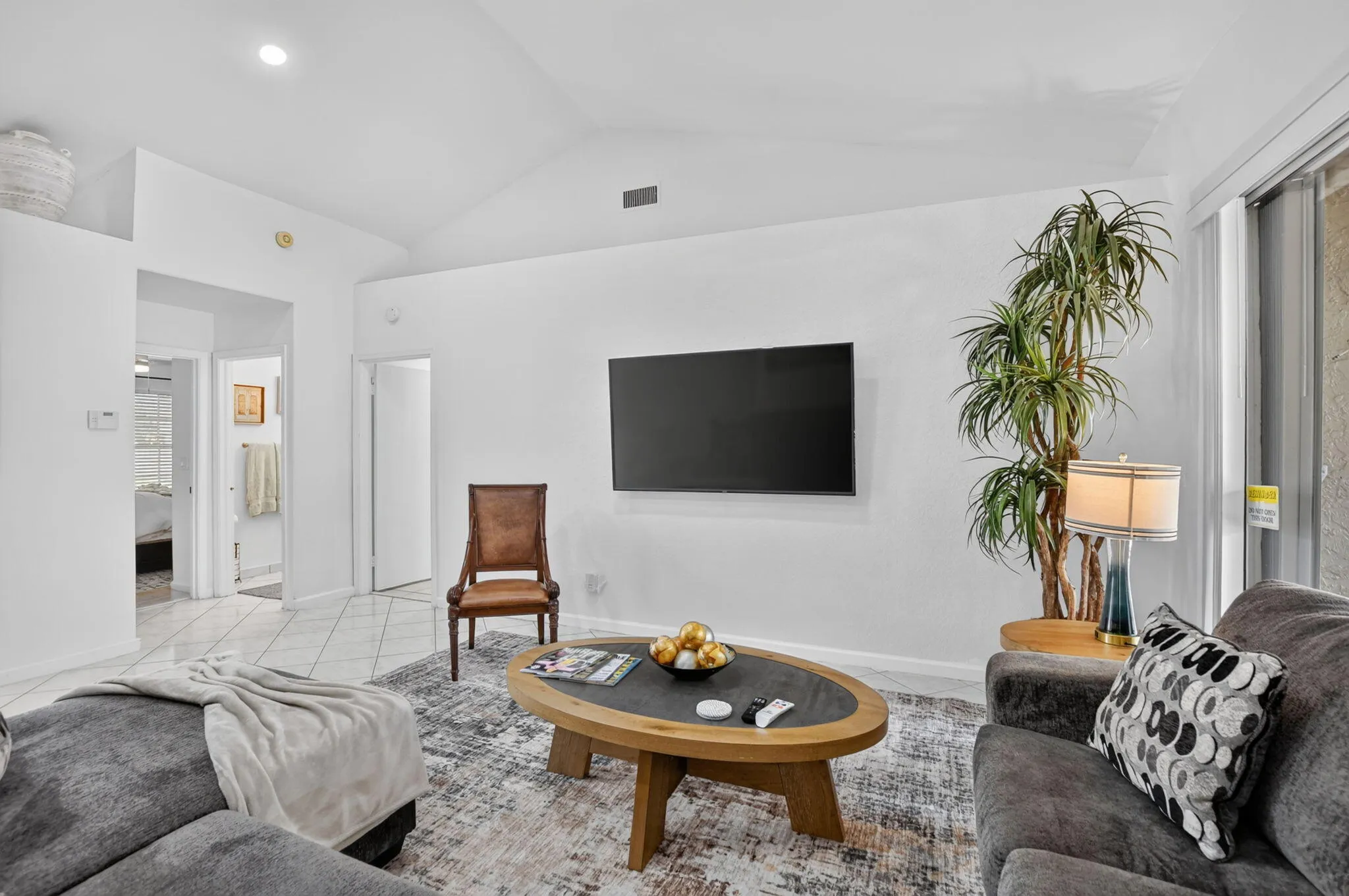 Vaulted ceiling, recessed lighting, tile flooring, and sliding glass door