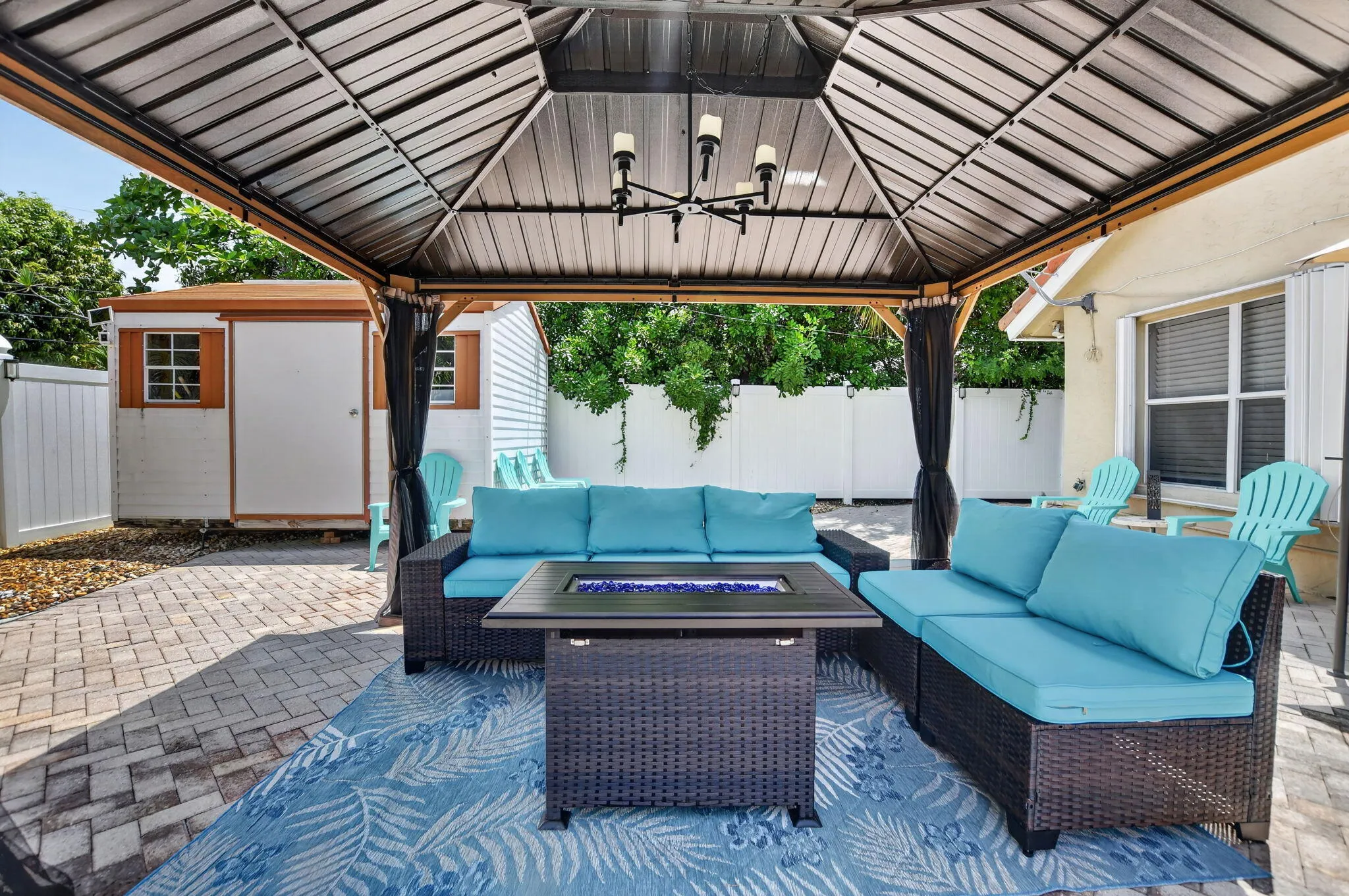 Paved patio featuring a built-in gazebo with a chandelier and privacy curtains
