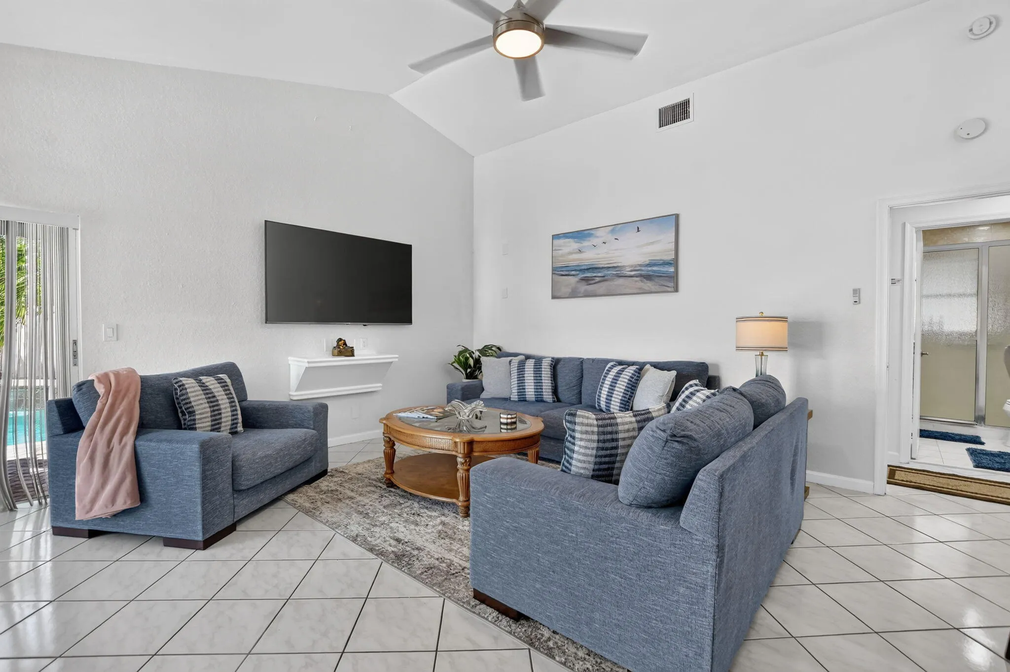 Vaulted ceiling with a ceiling fan, white tile flooring, sliding glass door to exterior, built-in shelving, and recessed lighting