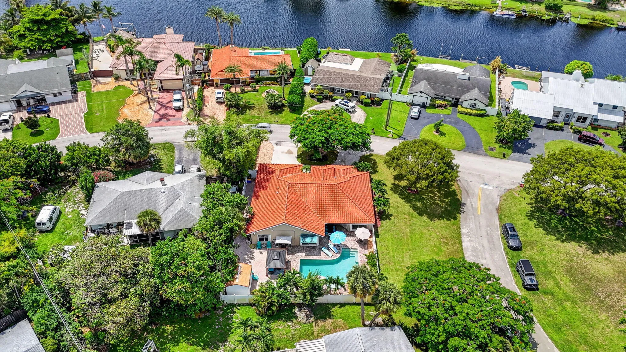 Property featuring a swimming pool, red tile roof, and mature landscaping