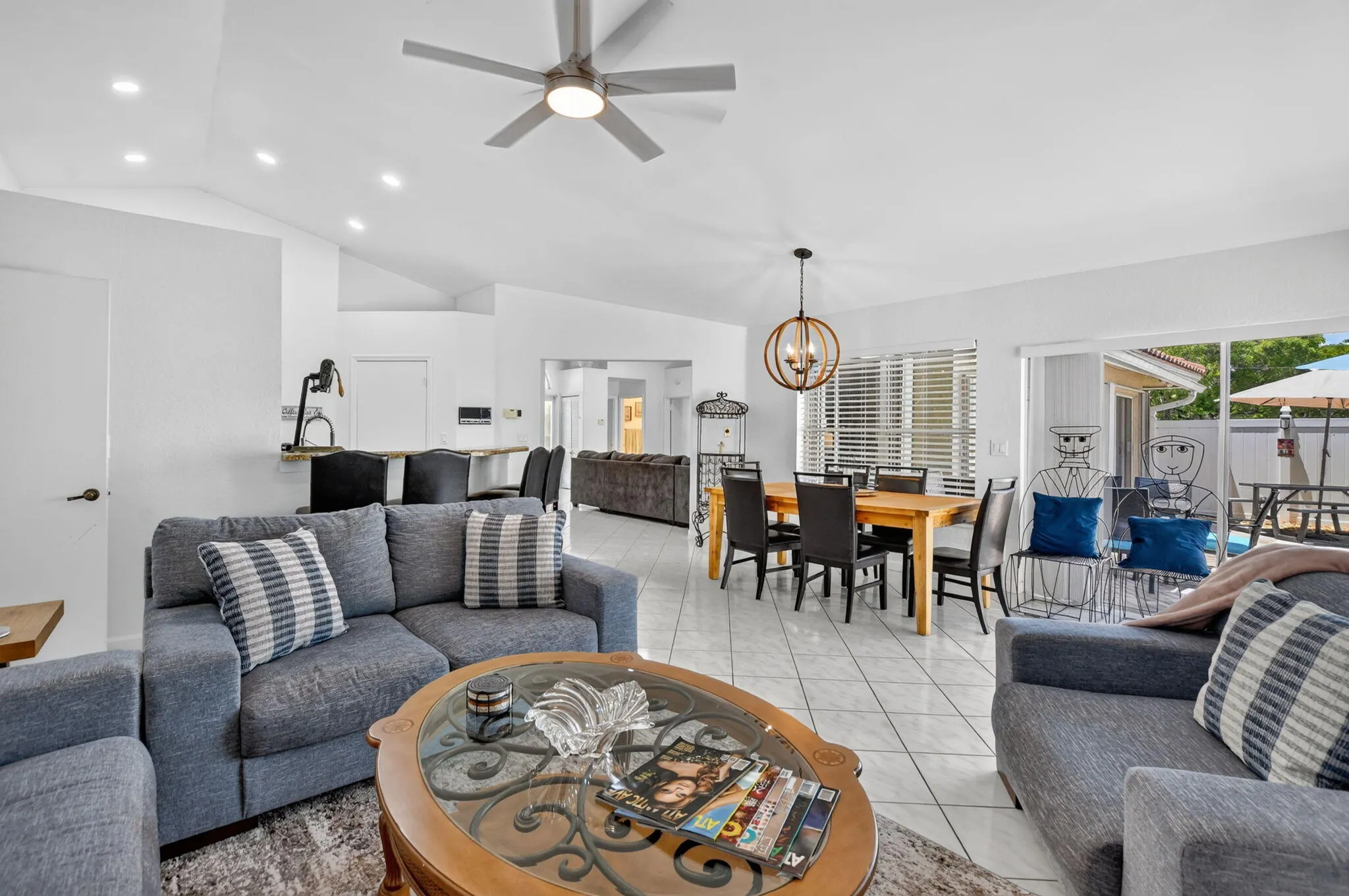 Vaulted ceiling, recessed lighting, tile flooring, contemporary ceiling fan, and sliding glass door