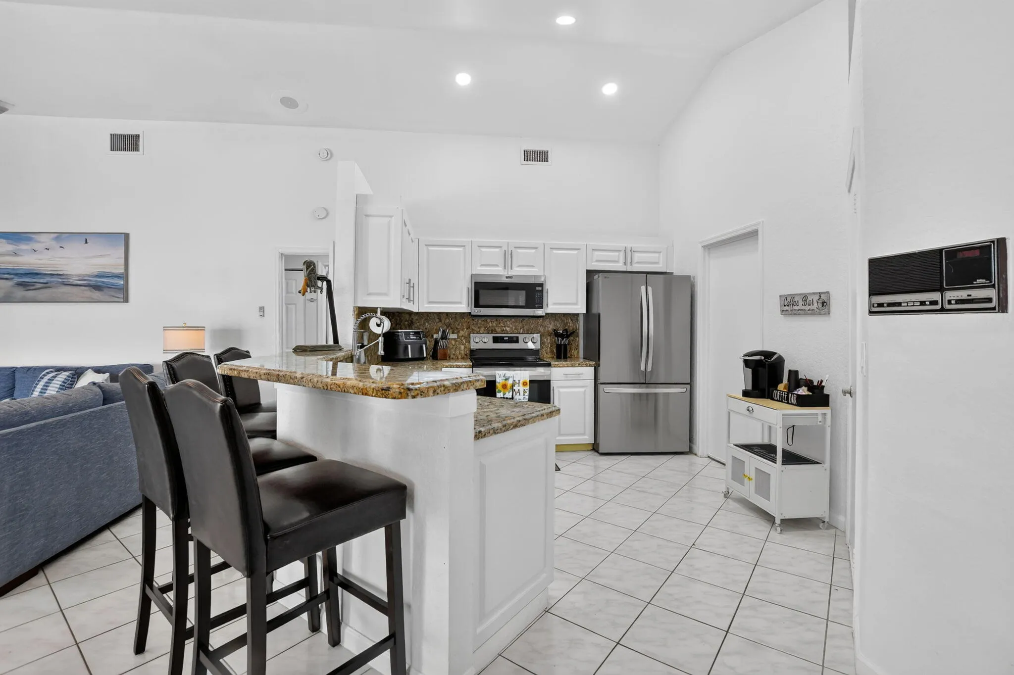 Kitchen featuring white cabinetry, stainless steel appliances, a counter-height breakfast bar, tile flooring, and recessed lighting