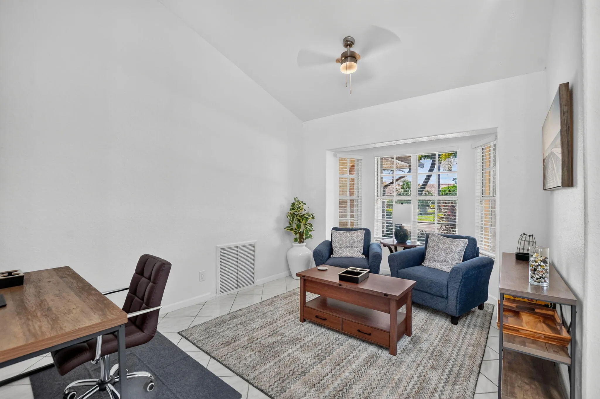 Vaulted ceiling, bay window, tile flooring, and a ceiling fan with integrated lighting