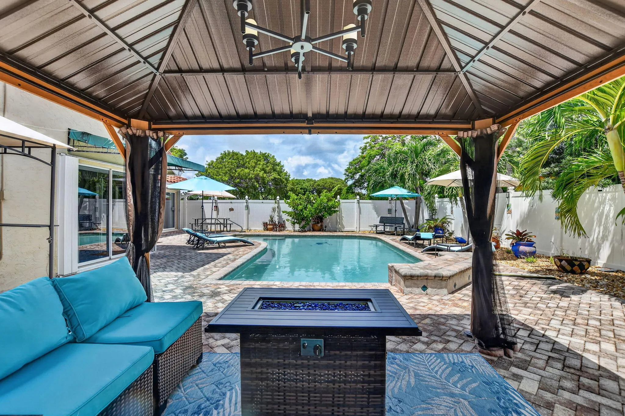 Covered patio with integrated lighting, paver patio, in-ground swimming pool, and privacy fencing