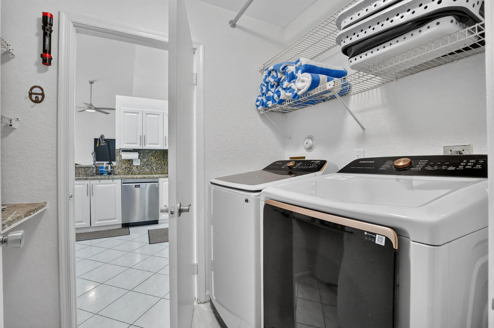 Dedicated laundry area featuring a washer and dryer, wire shelving, and tiled flooring