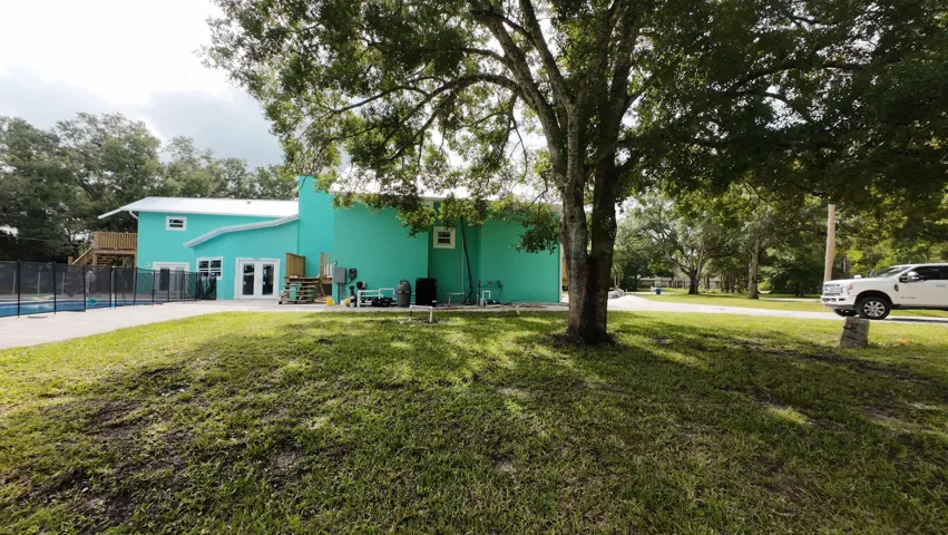 Exterior featuring a vibrant aqua finish, a white sloped roof, and a second-story wooden deck