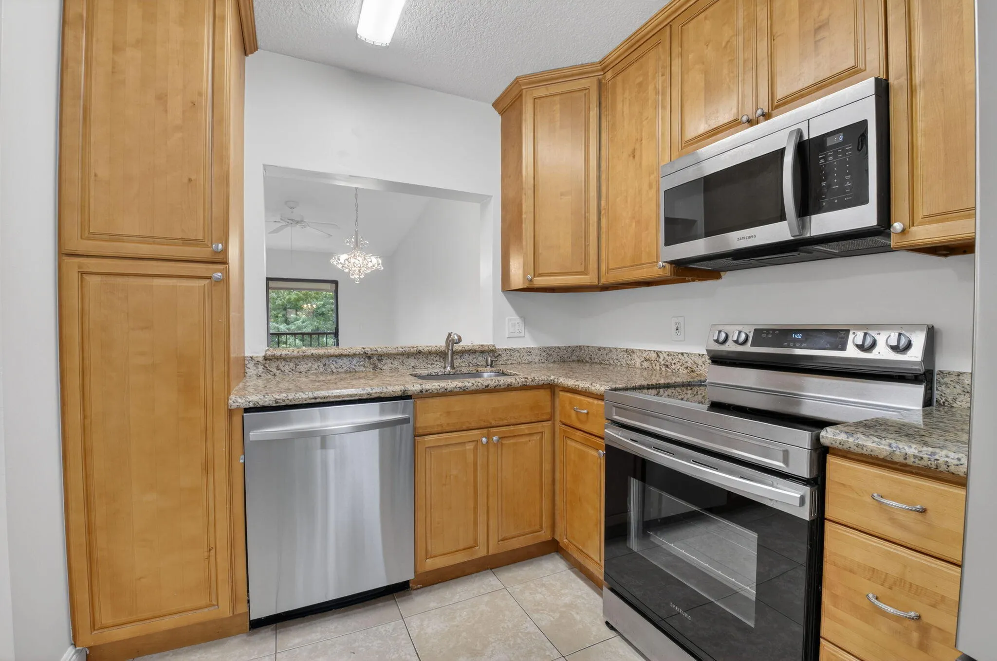 Kitchen featuring wood-finish cabinetry, stainless steel appliances, granite countertops, and tile flooring