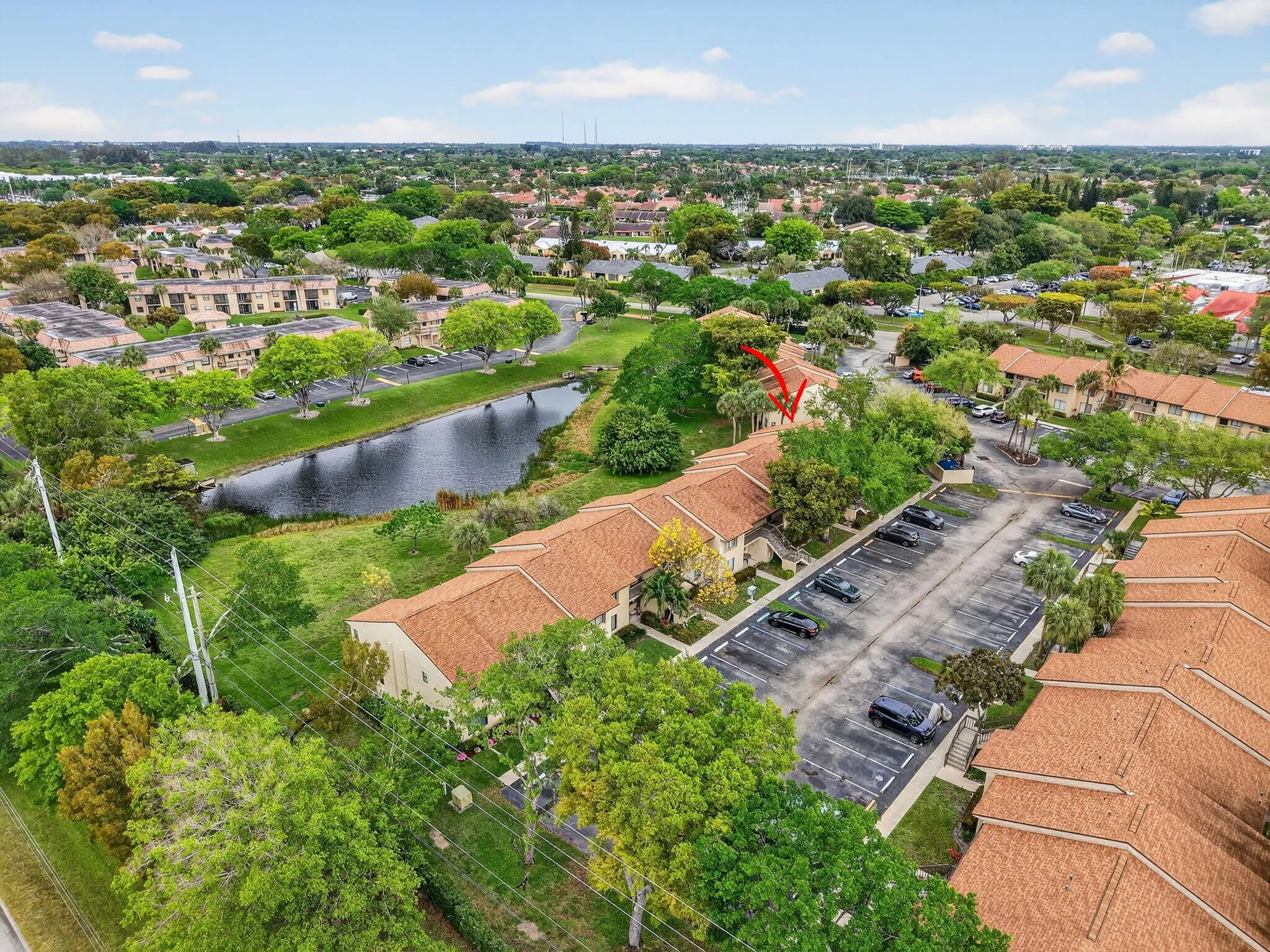 Community featuring a pond, mature trees, and ample parking