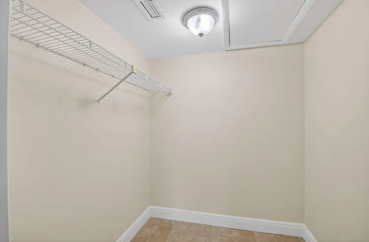Neutral wall finish, ceiling-mounted light fixture, tile flooring, and white wire shelving