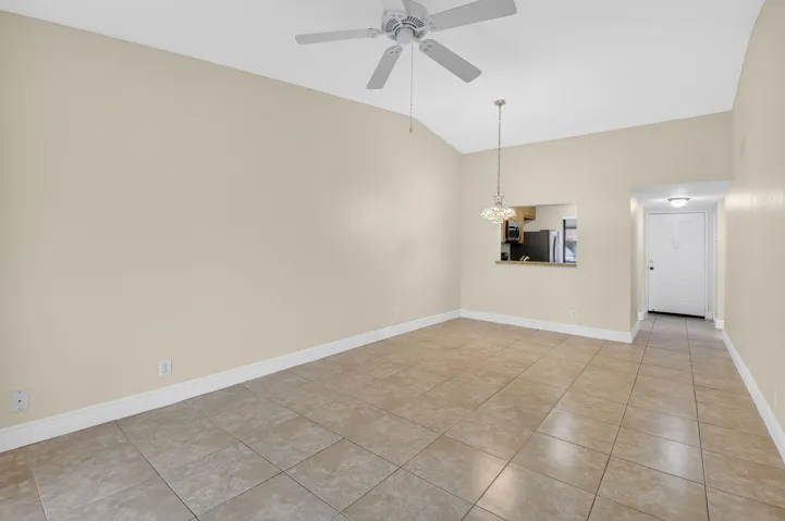 Vaulted ceilings with a ceiling fan, tile flooring, and a kitchen pass-through window