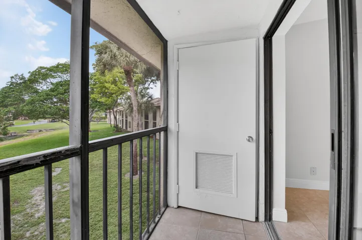 Screened balcony with a tiled floor, white door, and sliding glass door