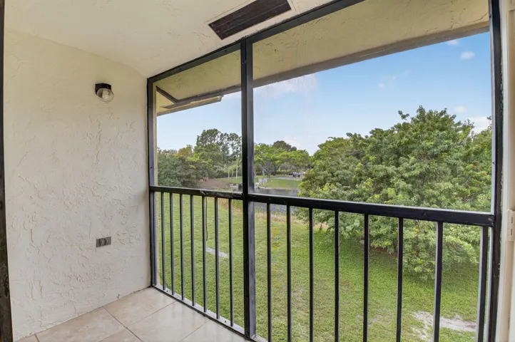 Enclosed balcony with tiled flooring, textured wall finish, and black metal railing