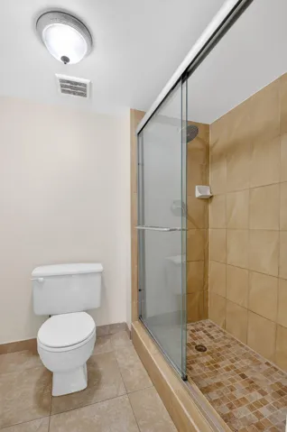 Shower with sliding glass enclosure, floor-to-ceiling tile, and mosaic tile shower pan