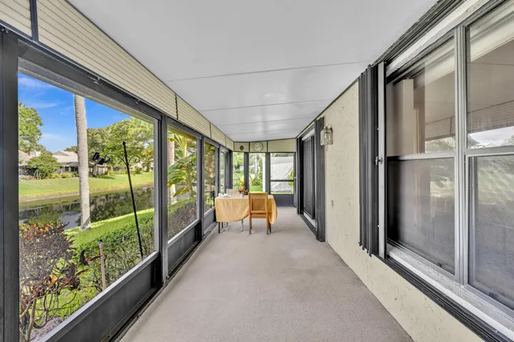 Enclosed screened porch with expansive glass panels framing manicured lawn and mature landscaping