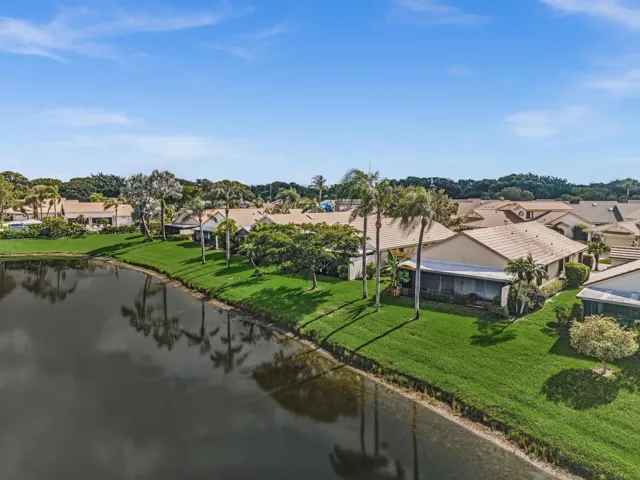 Waterfront property with extensive green space, mature palm trees, and a screened patio