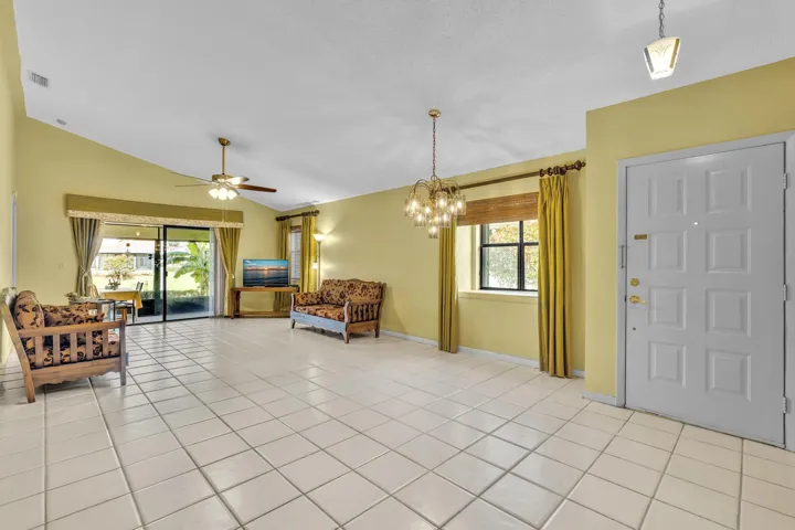 Vaulted ceiling, ceramic tile flooring, sliding glass door, ceiling fan, and front entry door