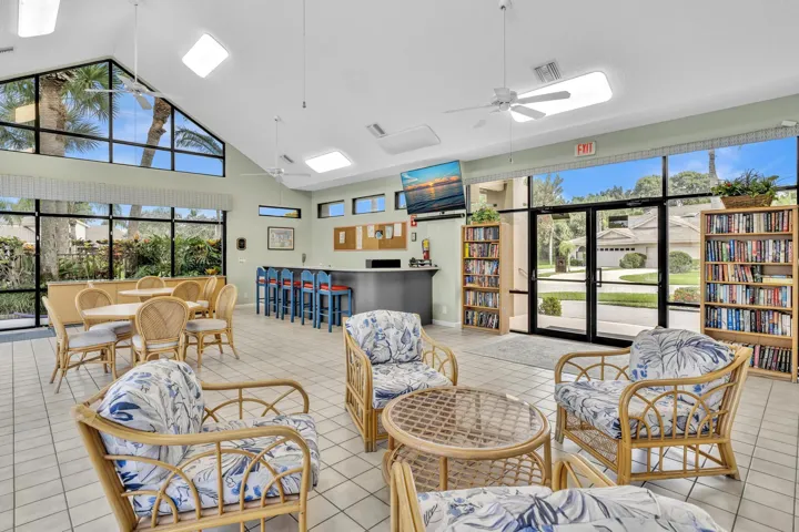 Vaulted ceiling with skylights and exposed beams, expansive window walls, integrated bar area, and tile flooring