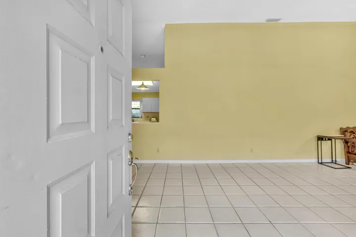 Entryway with a paneled door, ceramic tile flooring, and a recessed pass-through opening to the kitchen
